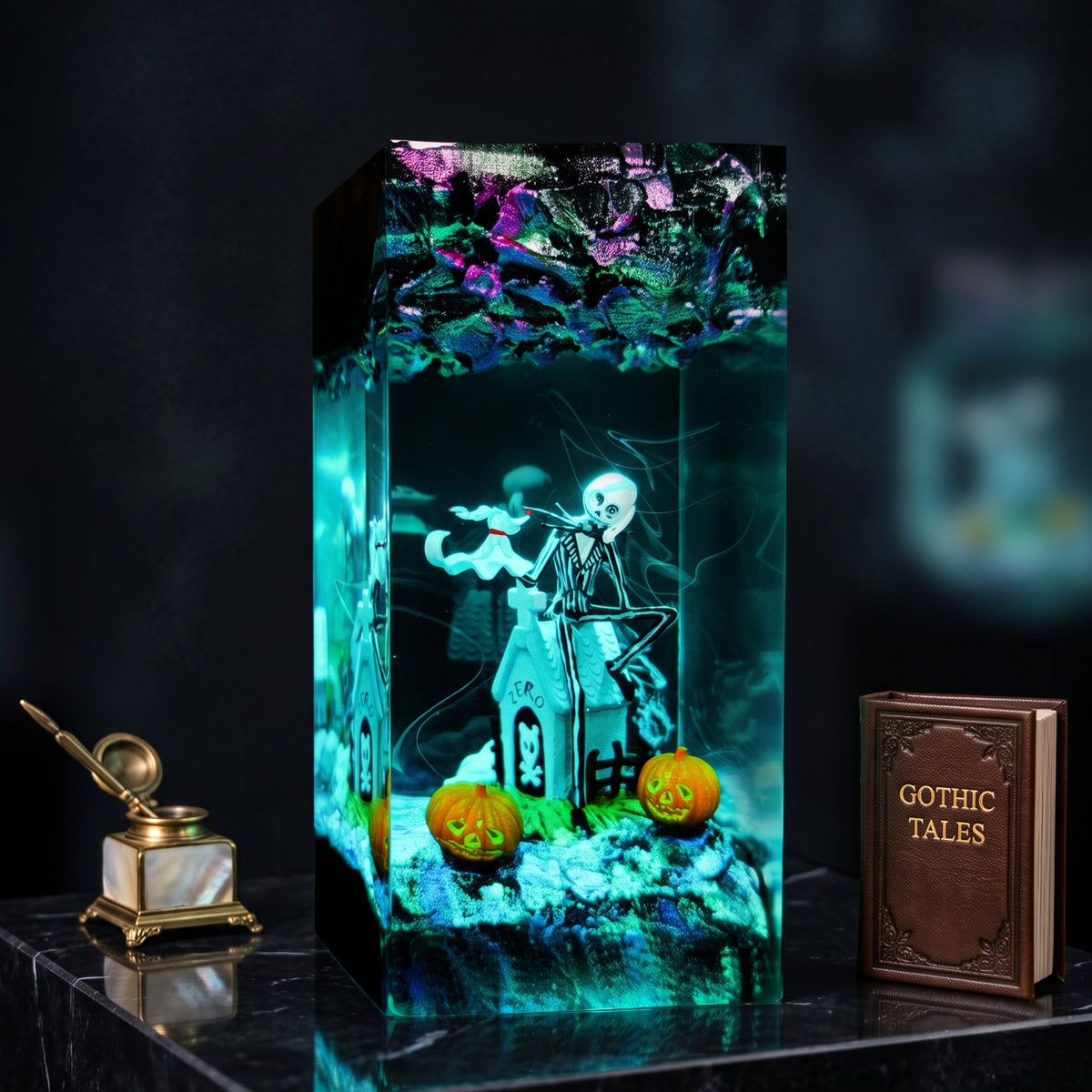 A gothic-themed resin candle holder featuring a skeleton playing a violin, a haunted house, two jack-o'-lanterns, and a spider on a dark gothic background, flanked by a miniature inkwell and a 'Gothic Tales' book.