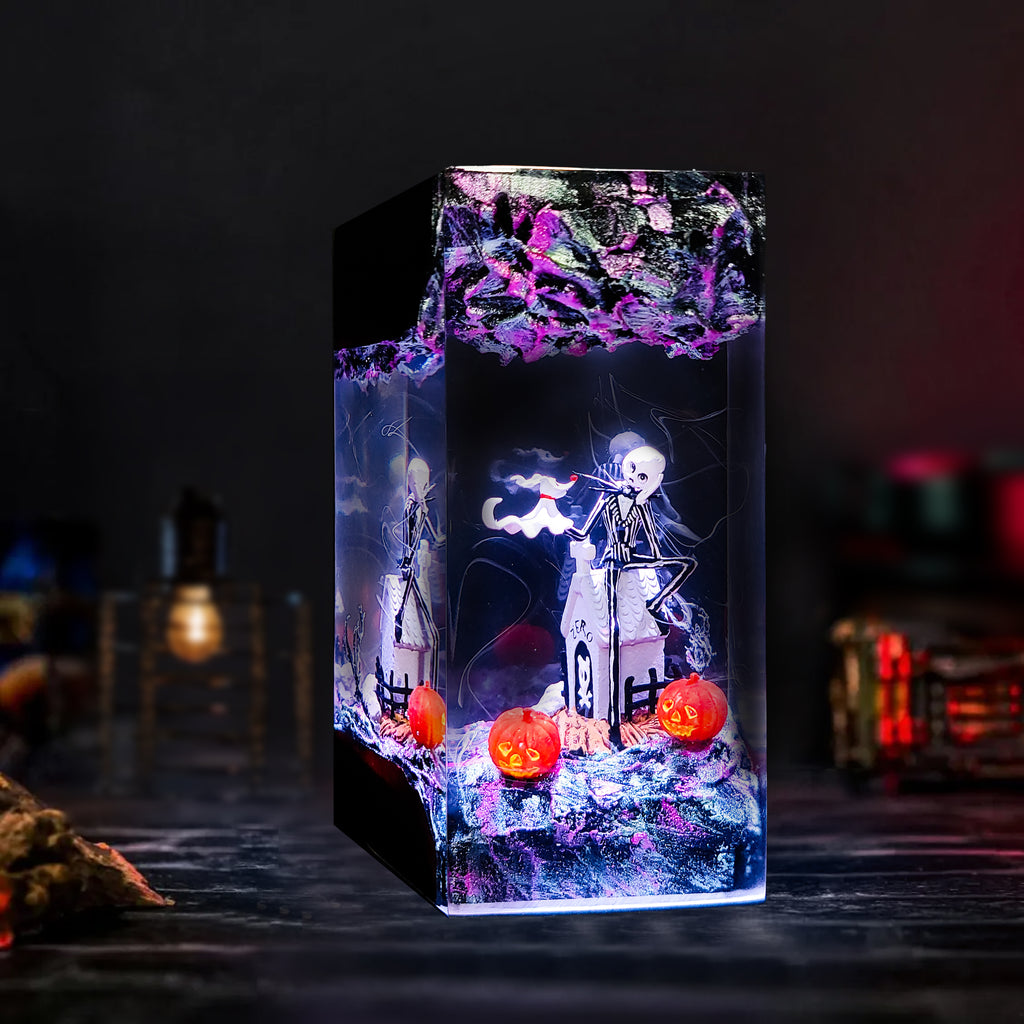 A rectangular acrylic resin candle holder with a Halloween-themed design, featuring a skeleton, a ghost, and glowing jack-o'-lanterns inside, set against a dark, moody background.